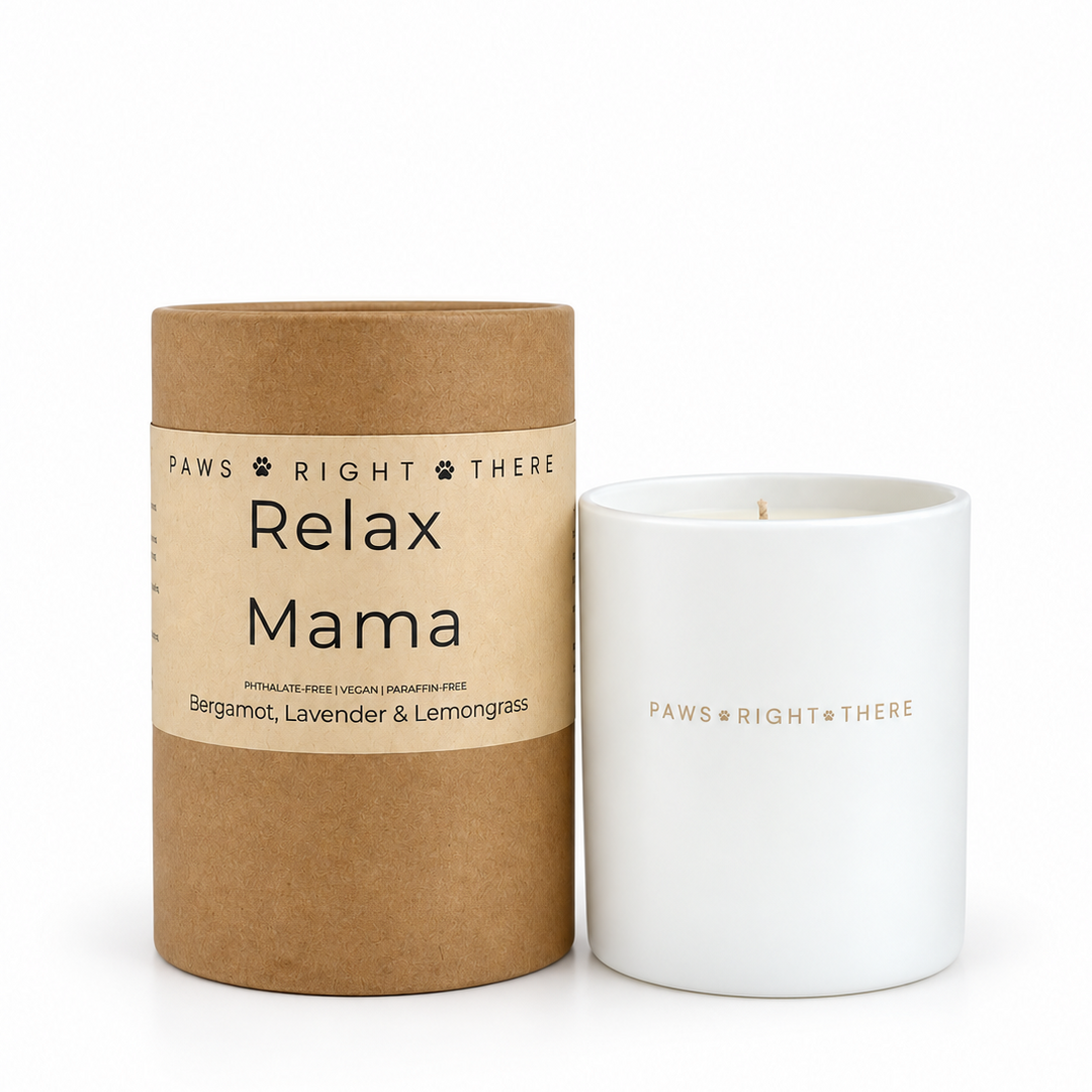 A white ceramic candle jar next to its brown kraft paper cylindrical packaging, both featuring the brand name 'PAWS RIGHT THERE' and the scent name 'Relax Mama'.